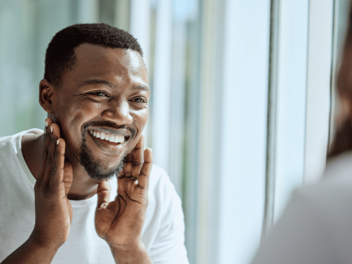 man looking in the mirror touching his face