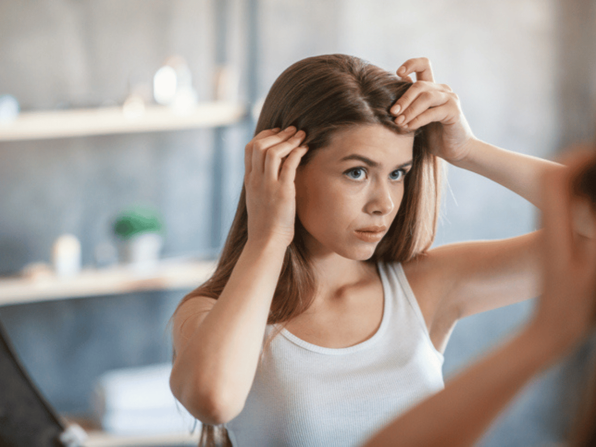 a girl looking at her hair in the mirror
